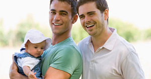 Smiling parents in a gay family holding a baby