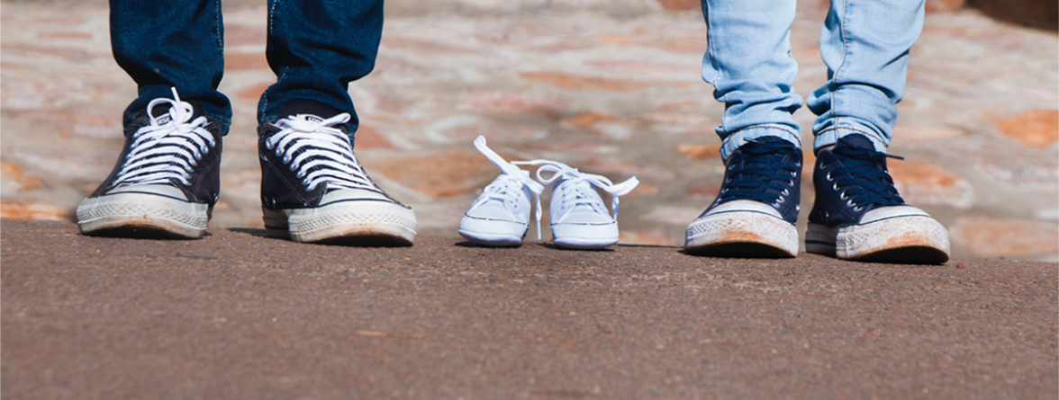 Image of a pair of gray low-top shoes between two persons wearing jeans