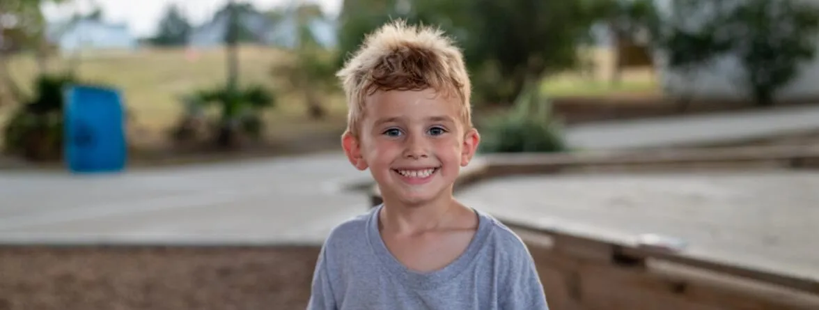 An image of a smiling boy in a blurry background.