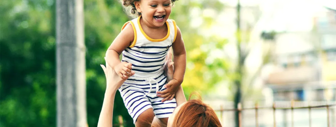 A happy child with a sweet smile, playing with her mother.