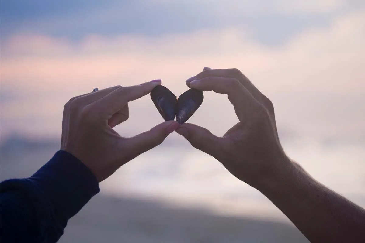 An image of two hands holding a stone shaped like a heart, with a blurred background
