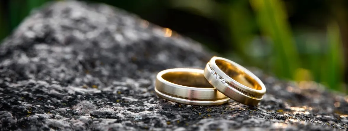 An image of a couple’s rings photographed on a large black rock.