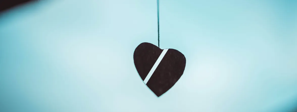 An image of a heart-shaped design hanging with a white line in the middle, set against a blue and white background