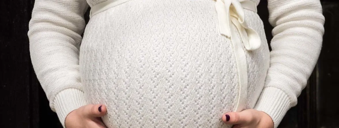 A pregnant woman holding her large belly.”