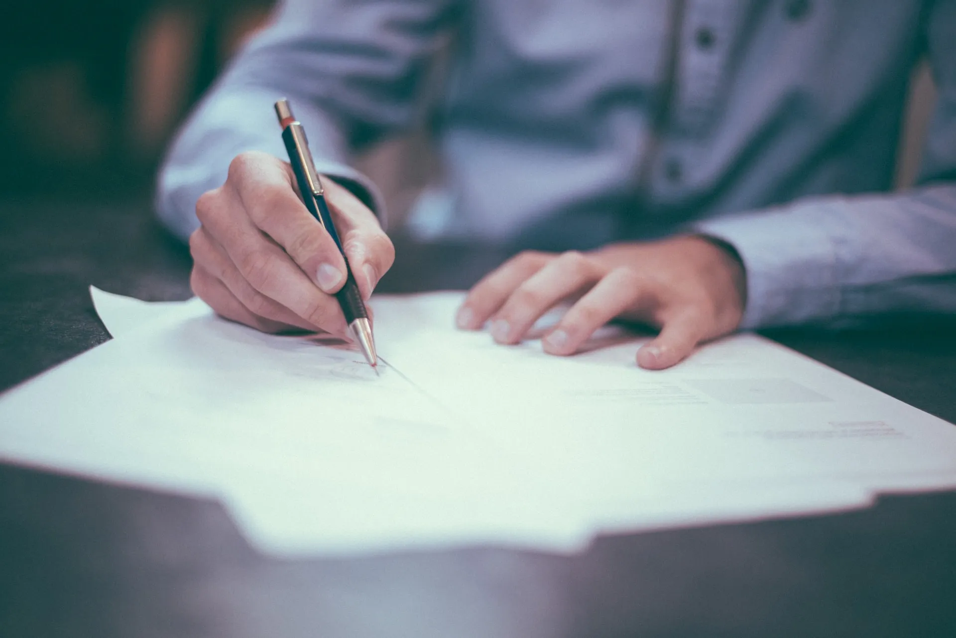 A man signing a paper in front of him.