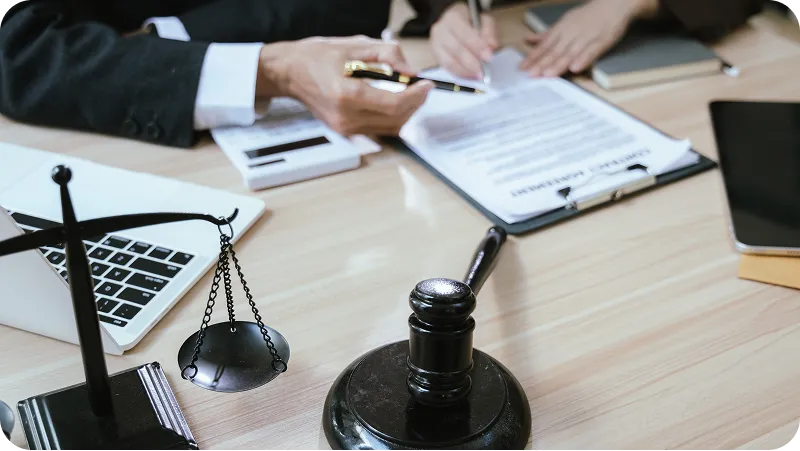 Legal attorney and a client alongside a contract agreement document being reviewed or signed.