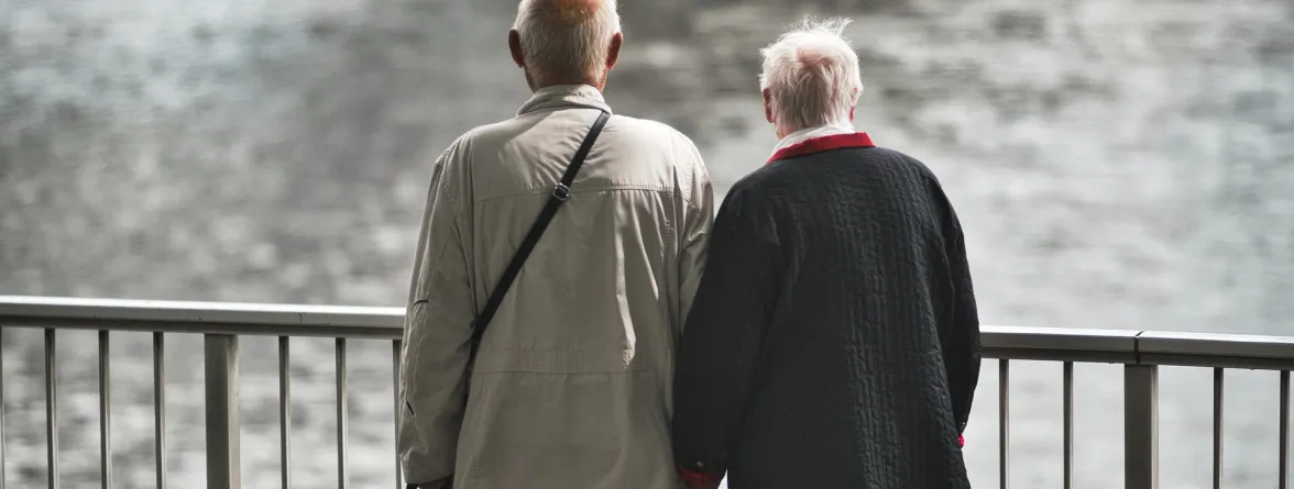 Two elderly people turned back and watching the sea.
