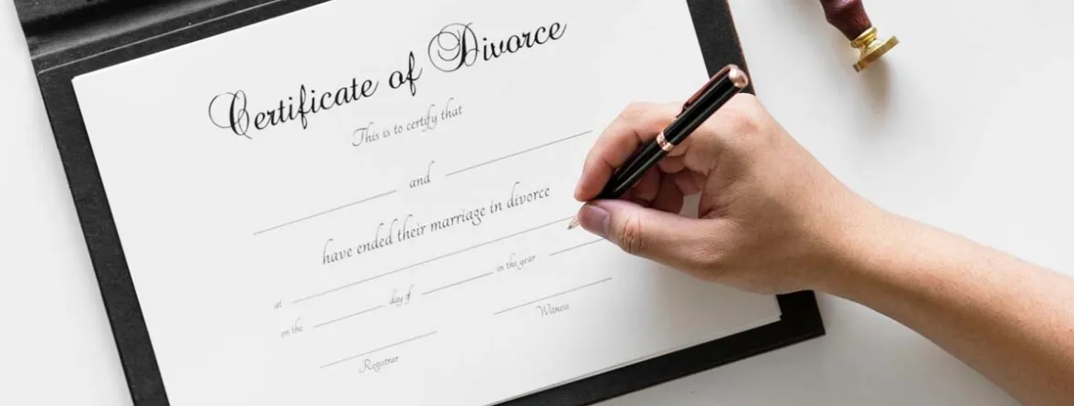 A divorce certificate with a hand poised to sign