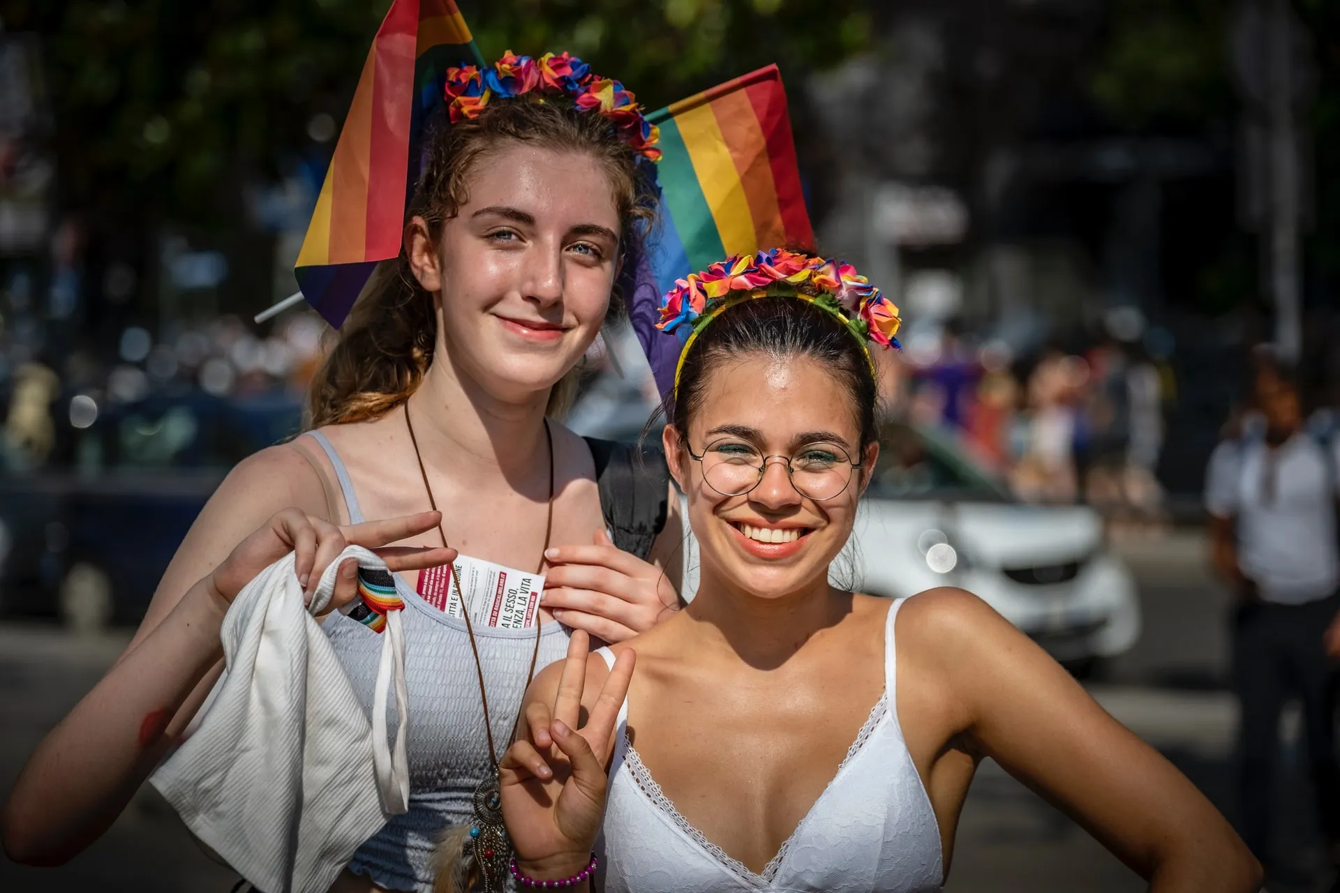 Two girls smiling and facing forward, making peace signs.