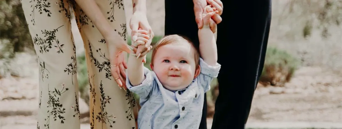 An image of a family, with a mother and father holding their baby while walking.