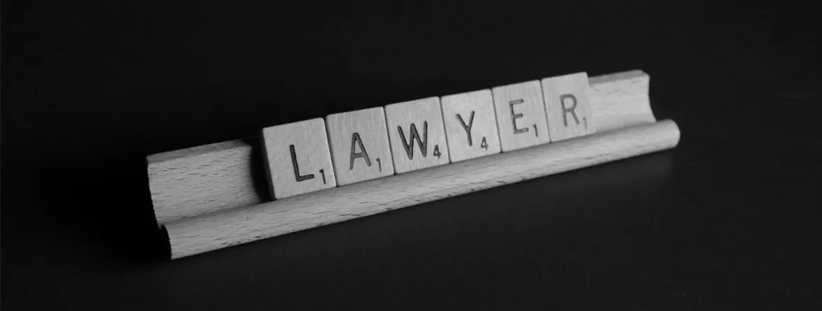 Scrabble tiles spell out 'LAWYER' against a dark background