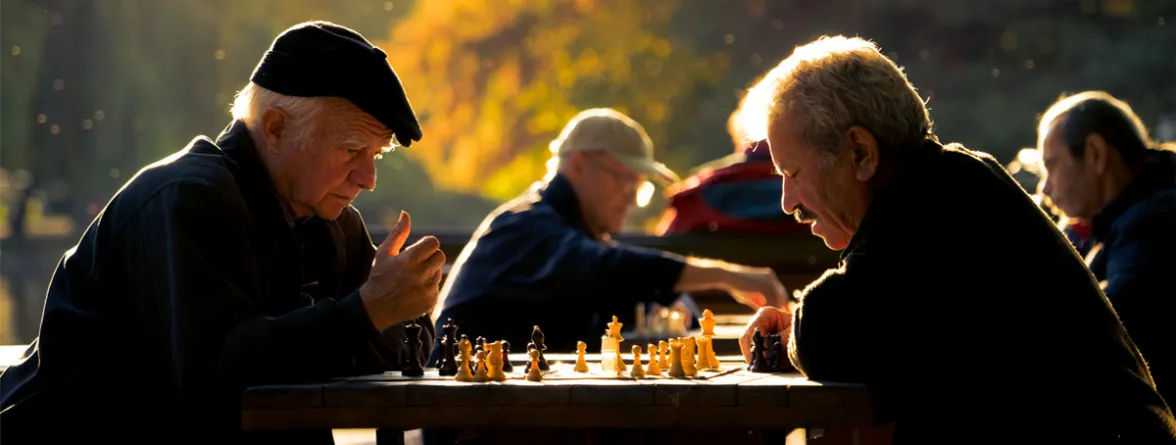 There are a few pairs of elderly men playing chess