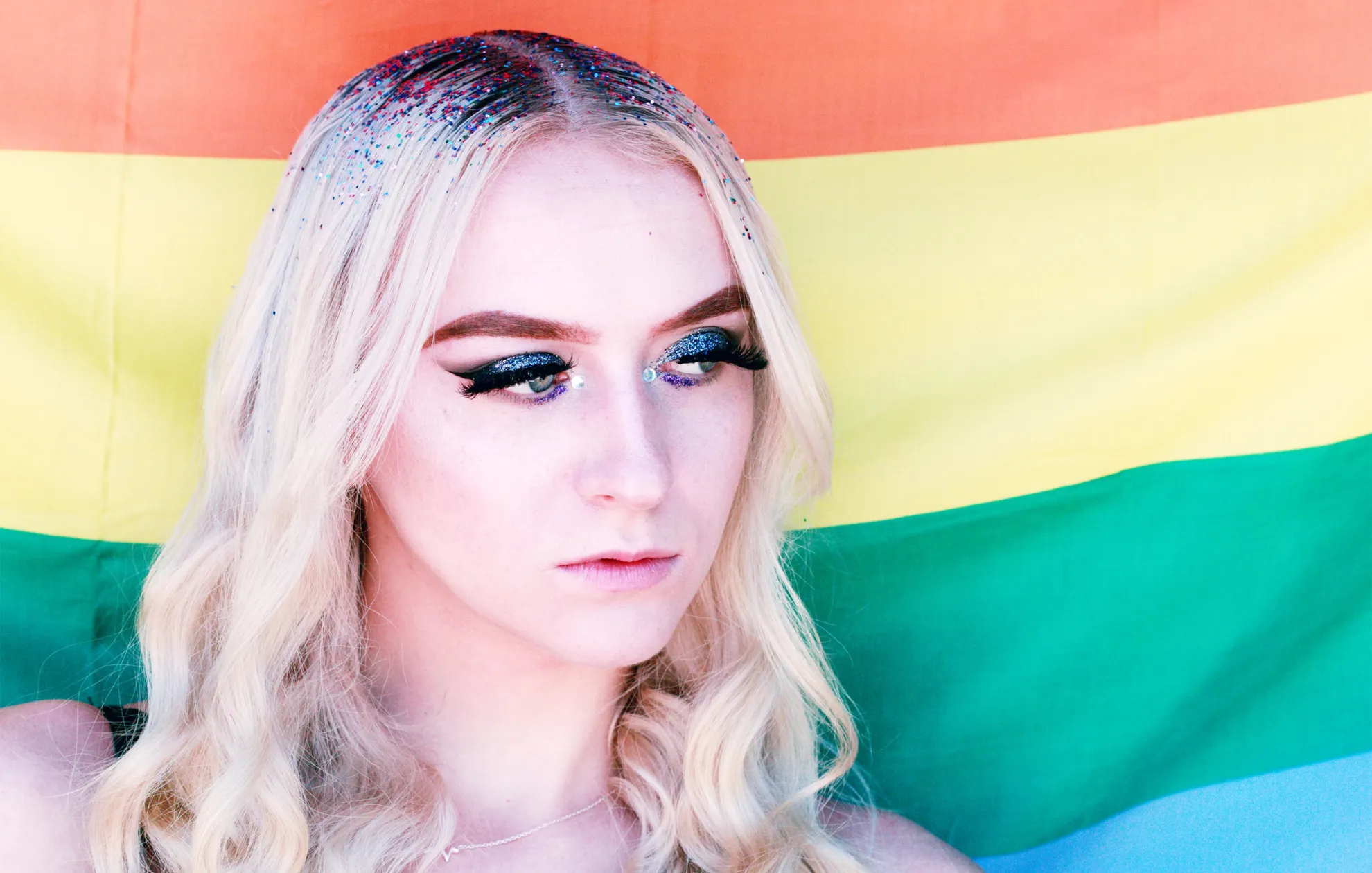 An image of a Woman against an LGBT flag background